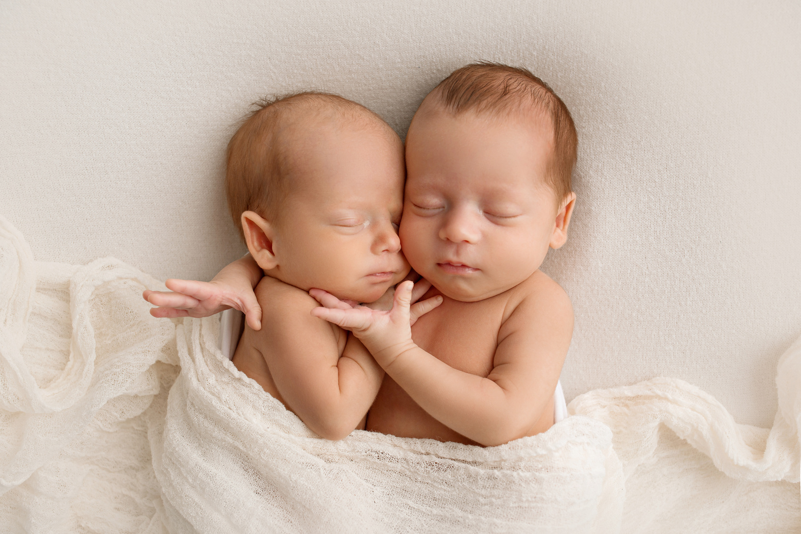 Tiny Newborn Twins Boys in White Cocoons on a White Background. a Newborn Twin Sleeps Next to His Brother. Newborn Two Twins Boys Hugging Each Other.Professional Studio Photography